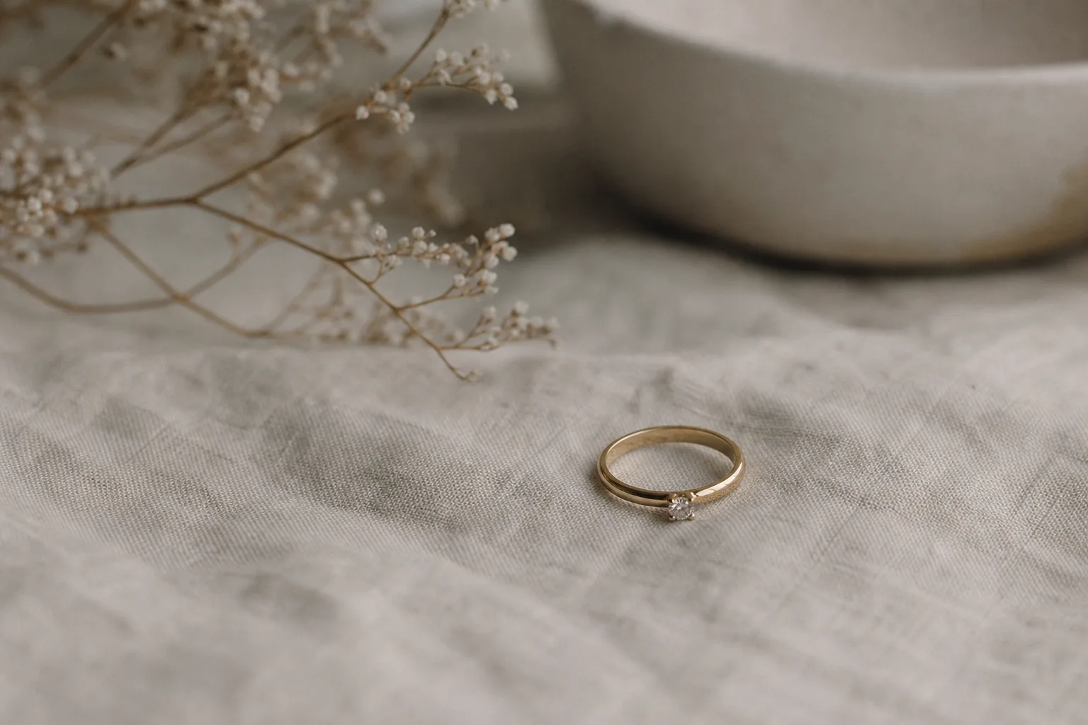 En ring med sten fotograferad nära mot mjukt tyg och naturligt fönsterljus.
